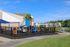 Charming apartment complex featuring a colorful playground beside a tranquil pond, perfect for families seeking a vibrant community.