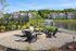 Charming outdoor seating area with fire pit, lush greenery, and a serene pond with fountain, perfect for relaxation and community gatherings.