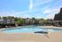 Inviting community pool area with sun loungers and lush greenery, perfect for relaxation and leisure.