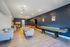 Chic lounge area featuring modern seating, a stylish bar counter, and a sleek shuffleboard table, all enhanced by elegant lighting and deep blue walls.