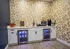 Chic kitchenette with stylish geometric wallpaper, featuring a coffee station, snack corner, and dual mini-fridges.