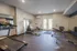 Modern fitness center with treadmill, exercise bikes, and a weight bench, offering a bright and well-equipped workout space.