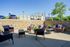 Inviting outdoor patio with stylish wicker seating, vibrant cushions, and lush greenery, perfect for relaxation and social gatherings.