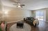 Inviting living room with modern ceiling fan, plush gray sofa, stylish decor, and ample natural light from sliding glass doors.
