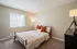 Cozy bedroom with soft lighting, featuring a neatly made bed and a large window allowing natural light to brighten the space.