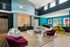 Modern apartment communal lounge with stylish seating, vibrant teal walls, and abundant natural light showcasing contemporary decor.