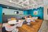 Chic lounge area with modern decor, featuring vibrant blue walls, comfortable seating, and stylish marble tables with pink chairs.