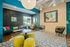 Chic communal space with vibrant teal and yellow accents, featuring modern seating and unique wall decor.