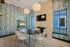 Chic dining area with modern design featuring a sleek oval table and stylish white chairs, complemented by artistic wallpaper and ambient lighting.