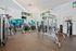 Modern fitness center with state-of-the-art equipment, featuring bright interiors and large windows for a vibrant workout environment.