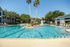 Luxurious swimming pool area with sun loungers and a central fountain surrounded by lush greenery, offering a resort-style living experience.