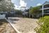 Modern apartment complex surrounded by lush greenery, featuring bright outdoor sand volleyball court, ideal for active living.