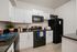 Modern kitchen with sleek black appliances, elegant white cabinetry, and inviting granite countertops.