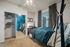 Chic bedroom featuring modern decor, cozy blue bedding, mirrored closet, and ample natural light.