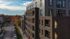 Modern apartment building with sleek architecture and large windows, nestled in a vibrant neighborhood with colorful autumn trees and a charming street view.
