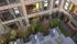 Modern apartment complex courtyard with lush greenery, stylish balconies, and inviting patio seating for relaxation.