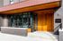 Modern apartment entrance with elegant brick facade, large windows, and inviting wood paneling.