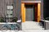 Chic modern apartment entrance with brick facade, inviting steps, and a vibrant teal bicycle for urban living appeal.