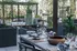 Chic outdoor terrace featuring a stylish dining setup with elegant dishware, surrounded by lush greenery and a cozy fire pit.