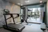Modern apartment gym with state-of-the-art treadmill, exercise bike, and scenic outdoor patio view through large glass doors.