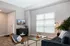 Modern living room with elegant decor, featuring a comfortable sofa, stylish chair, and large window providing ample natural light.