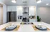 Modern kitchen with elegant white cabinetry, stainless steel appliances, and chic dining setup, featuring stylish pendant lighting and lush greenery.
