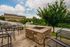 Charming outdoor patio with cozy seating and a rustic stone fire pit, overlooking lush greenery and scenic views.