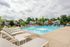 Inviting outdoor swimming pool area surrounded by comfortable loungers and vibrant greenery, perfect for relaxation in a charming residential community.