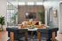Chic modern living room featuring a stylish mustard sofa, plush accent pillows, and elegant black armchairs. Natural light floods the space through large windows, enhancing the sleek decor and green plants.