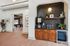 Sleek modern living space featuring a stylish coffee bar with black tile backsplash, elegant wooden cabinetry, and natural light filtering through the spacious room.