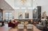 Luxurious living room featuring high ceilings, elegant chandeliers, and a chic layout with a deep red sofa, curved seating area, and a modern fireplace.