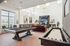 Luxury game room in a modern apartment featuring a sleek pool table, shuffleboard, elegant seating area, and large windows for natural light.