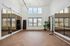 Elegant fitness room with floor-to-ceiling mirrors, hardwood floors, and ample natural light from large windows, ideal for yoga and pilates.