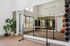 Modern fitness studio with mirrored wall, barre, and vibrant exercise equipment, featuring elegant wooden flooring and lush plants.