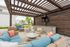 Chic outdoor lounge area with modern wicker furniture, vibrant cushions, and a stylish pergola. Ideal for relaxation and entertaining guests.