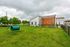 Charming fenced backyard with lush green lawn, modern white and wooden exterior, and playful dog park equipment, perfect for families and pets.