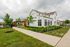 Charming residential complex featuring modern white buildings with large windows, lush green landscaping, and a quaint walkway.
