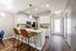 Contemporary kitchen with sleek white cabinets, modern appliances, and a stylish breakfast bar with leather stools.