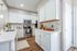 Modern kitchen with sleek white cabinetry, stainless steel appliances, and elegant gold accents on hardware and faucet.