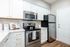 Modern kitchen with sleek stainless steel appliances, white cabinetry with gold accents, and elegant wood flooring.