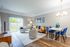 Chic modern living and dining area with elegant decor, featuring a cozy sofa, stylish chairs, and a bright, airy atmosphere overlooking a lush garden.