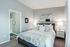 Modern bedroom with cozy decor, plush carpeting, and adjacent bathroom in an elegant apartment setting.