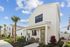 Contemporary two-story home with elegant facade, tropical landscaping, and inviting front porch under a bright blue sky.