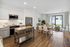 Bright open-concept kitchen and living area with modern appliances, sleek cabinetry, and stylish dining space leading to a sunlit patio.