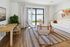 Bright and modern living room with stylish furniture, wooden floor, and sliding glass door leading to a sunny patio.