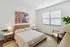Bright and cozy bedroom with modern wooden furniture, stylish decor, and a large window offering natural light.