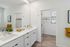 Modern bathroom with dual sinks, elegant white cabinetry, and abundant natural light leading to a spacious walk-in closet.