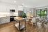 Modern open-concept kitchen and living room with natural light, sleek appliances, and a cozy seating area overlooking a lush garden.
