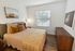 Bright and cozy bedroom with elegant decor, featuring a comfortable bed, modern lighting, and large window with outdoor view.