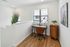Bright and modern small home office with sleek wooden flooring, stylish desk, and cozy chair, perfect for productivity.